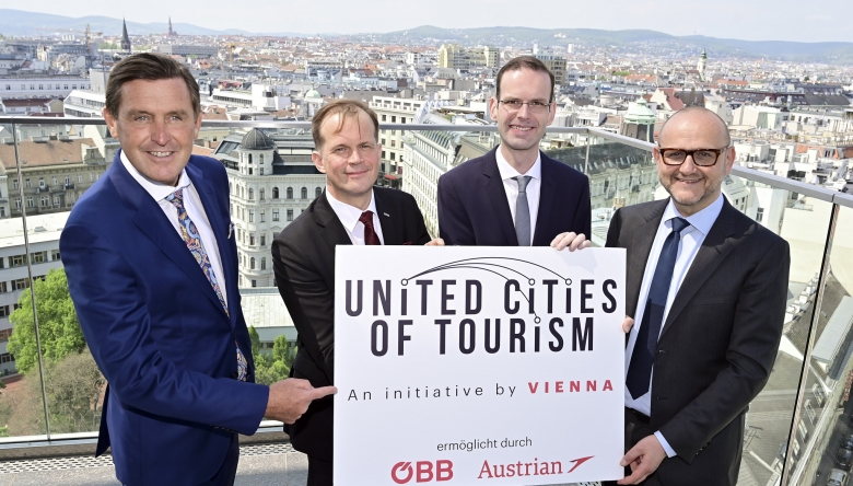 Vier Männer halten ein Schild mit der Aufschrift „United Cities of Tourism“ in die Höhe. (Bild: wientourismus © PID/ Christian Jobst)