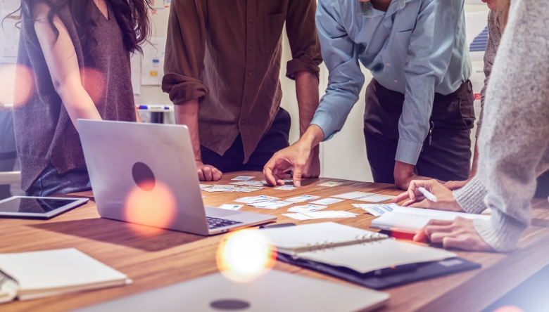 Junge Menschen gemeinsam über einen Tisch mit Aufzeichnungen gebeugt. (Bild © Adobe Stock/Yingyaipumi)