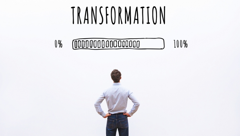 In Zeiten akuten Fachkräftemangels müssen Unternehmen sich anpassen, um Arbeitskräfte zu finden und zu halten. (Foto: istockphoto.com/anyaberkut) Foto von einem Mann von hinten, er schaut auf eine Wand mit dem Wort "Transformation" und einem Ladebalken (Foto: istockphoto.com/anyaberkut)