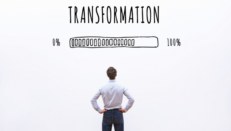 Foto von einem Mann von hinten, er schaut auf eine Wand mit dem Wort "Transformation" und einem Ladebalken (Foto: istockphoto.com/anyaberkut)