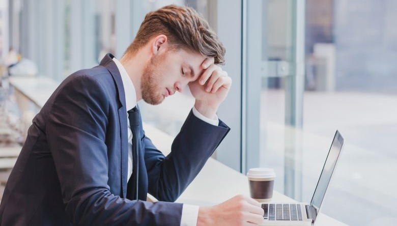 Mann in Anzug vor Laptop mit pessimistischer Miene