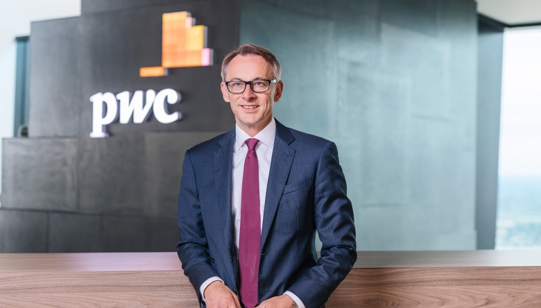Foto von Rudolf Krickl vor einer Wand mit pwc-Logo (Foto © PwC Österreich)