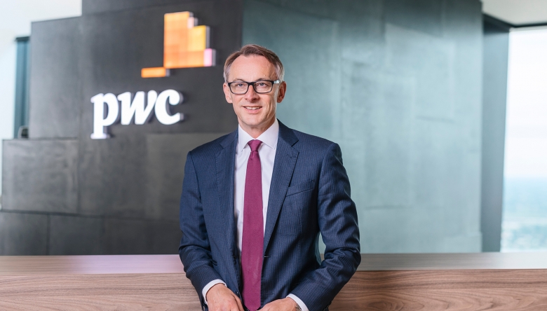 Foto von Rudolf Krickl vor einer Wand mit pwc-Logo (Foto © PwC Österreich)