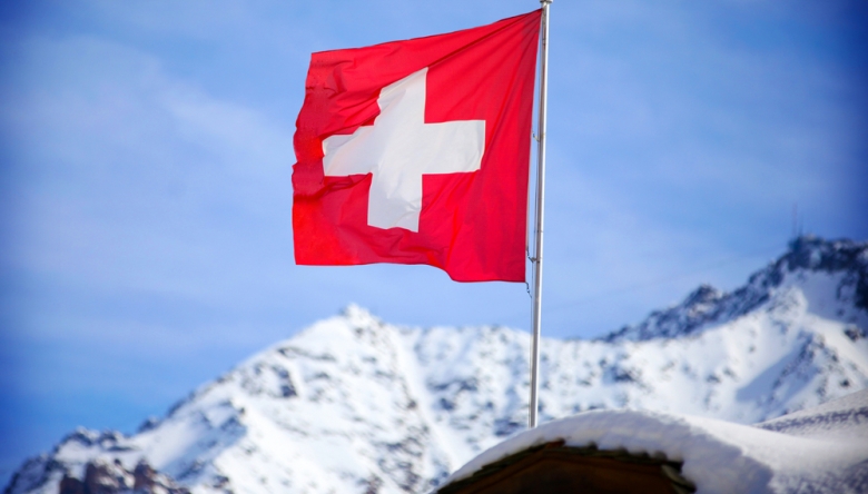 Weltweit ist die Schweiz führend bei der Wahrnehmung ihrer Wirtschaft und ihrer Lebensqualität. (Foto: Shutterstock/Marco Scisetti) Schweizer Fahne auf Bergspitze weht im Wind C Shutterstock