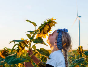 Mädchen riecht an einer Sonnenblume (Bild © Nestlé)