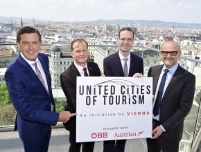 Vier Männer halten ein Schild mit der Aufschrift „United Cities of Tourism“ in die Höhe. (Bild: wientourismus © PID/ Christian Jobst)