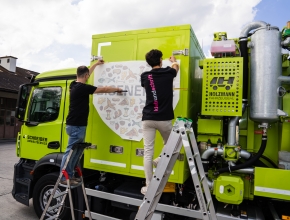 Zwei Mitarbeiter der Sozialfirma klebundschrift bekleben ein Fahrzeug. Bild (c) Die Sozialfirma