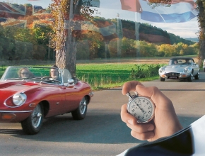 Im Hintergrund sieht man Oldtimer Autos ein Rennen fahren, im Vordergrund eine Hand die eine Stoppuhr hält (Foto: automotive experience gmbh)