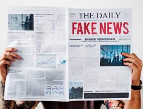 Mann hält Zeitung hoch mit Überschrift "Fake News"
