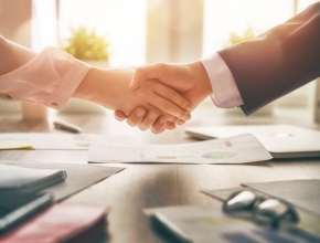 Mann und Frau in Business Kleidung schütteln sich die Hand