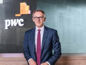 Foto von Rudolf Krickl vor einer Wand mit pwc-Logo (Foto © PwC Österreich)