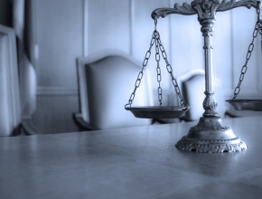 Foto mit einer Waage im Vordergrund, Gerichtssaal im Hintergrund