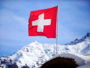 Weltweit ist die Schweiz führend bei der Wahrnehmung ihrer Wirtschaft und ihrer Lebensqualität. (Foto: Shutterstock/Marco Scisetti) Schweizer Fahne auf Bergspitze weht im Wind C Shutterstock