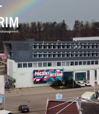 Foto von einem Gebäude mit einem Plakat von Projekt Interim an der Fassade